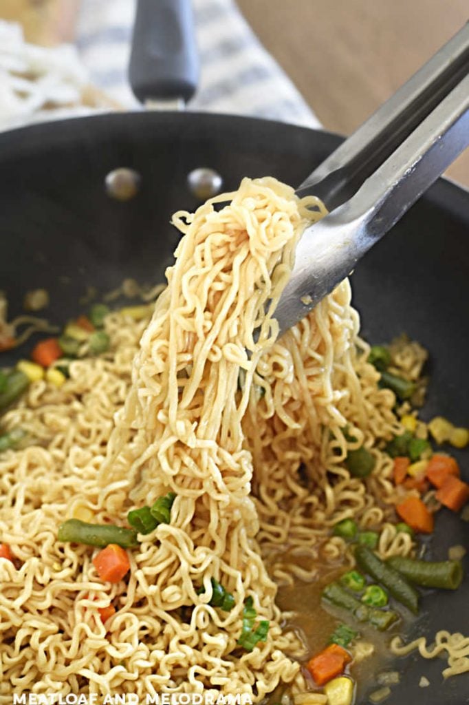 cooked ramen noodles in kitchen tongs in wok