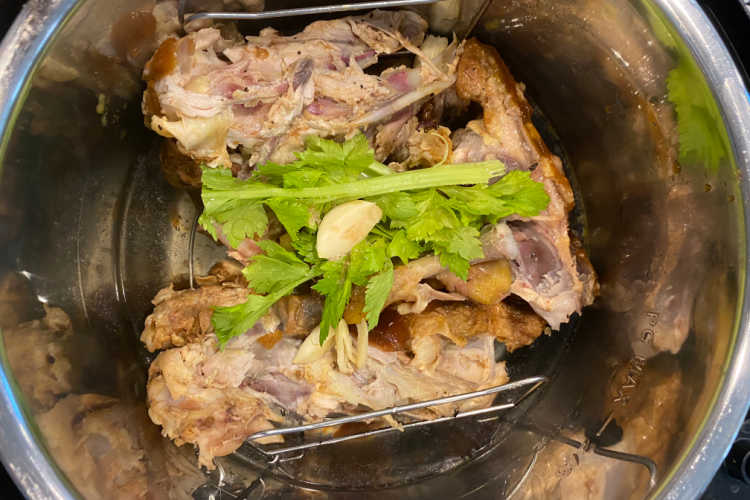 carcass from roasted rotisserie chicken in pressure cooker with celery and garlic