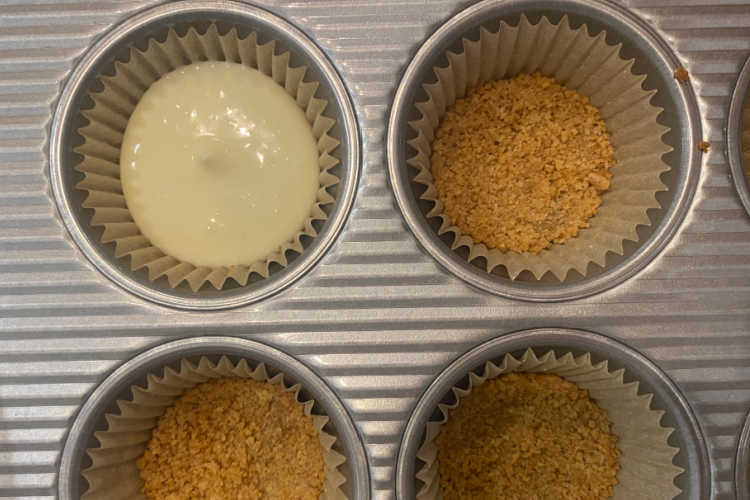 pour cheesecake filling over graham cracker crust in muffin tin