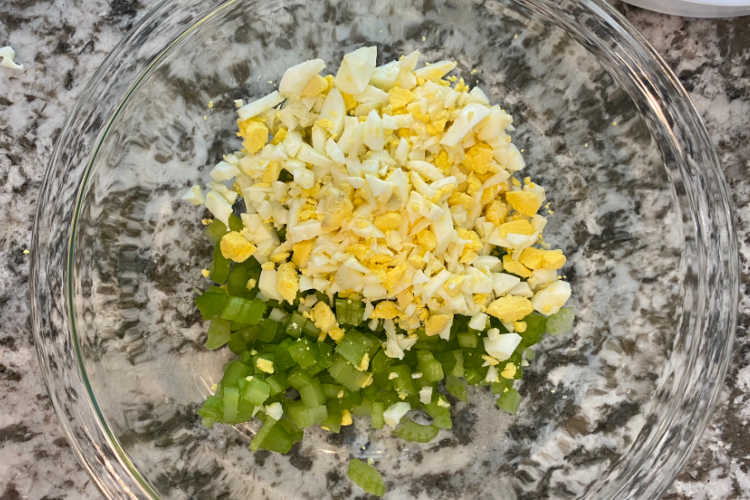 chopped celery and chopped hard boiled eggs in glass mixing bowl