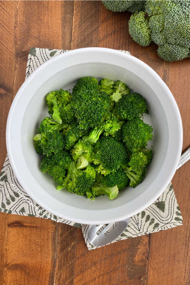 cooked broccoli in white serving bowl on table