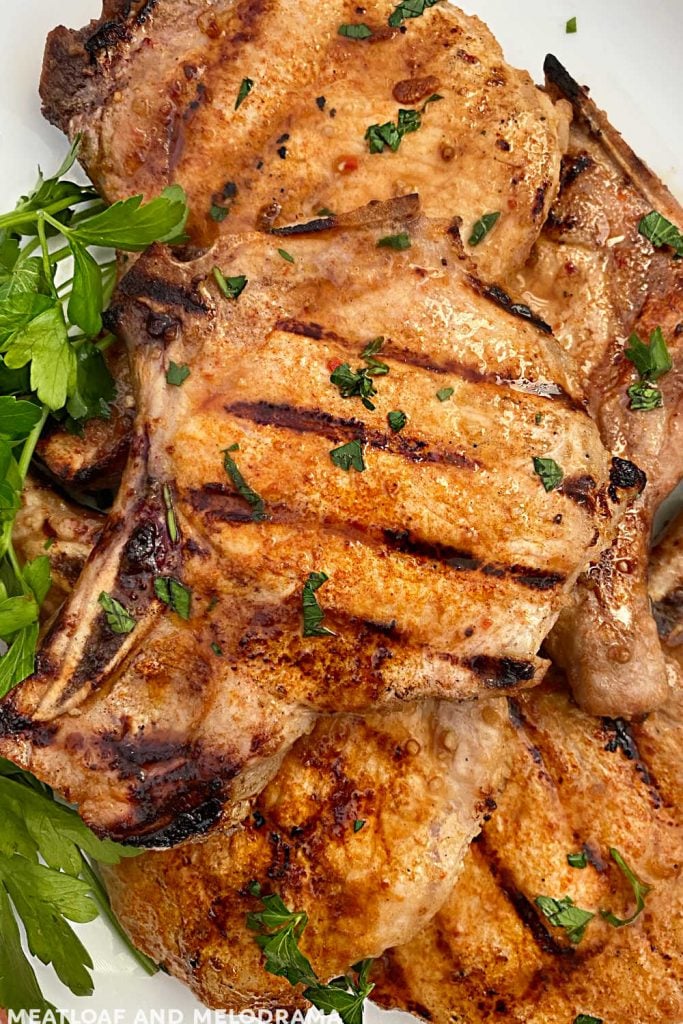 platter of grilled pork chops topped with parsley