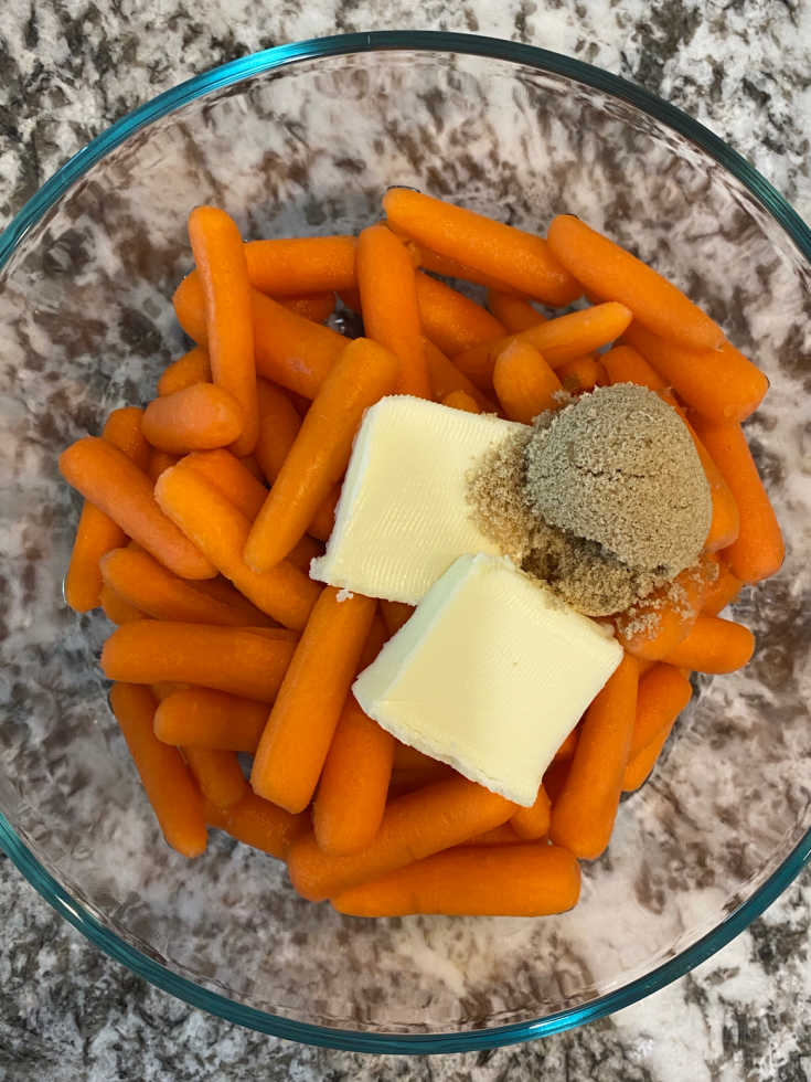 raw baby carrots in glass dish with butter and brown sugar