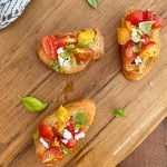 bruschetta with red and yellow tomatoes and basil with feta cheese on cutting board