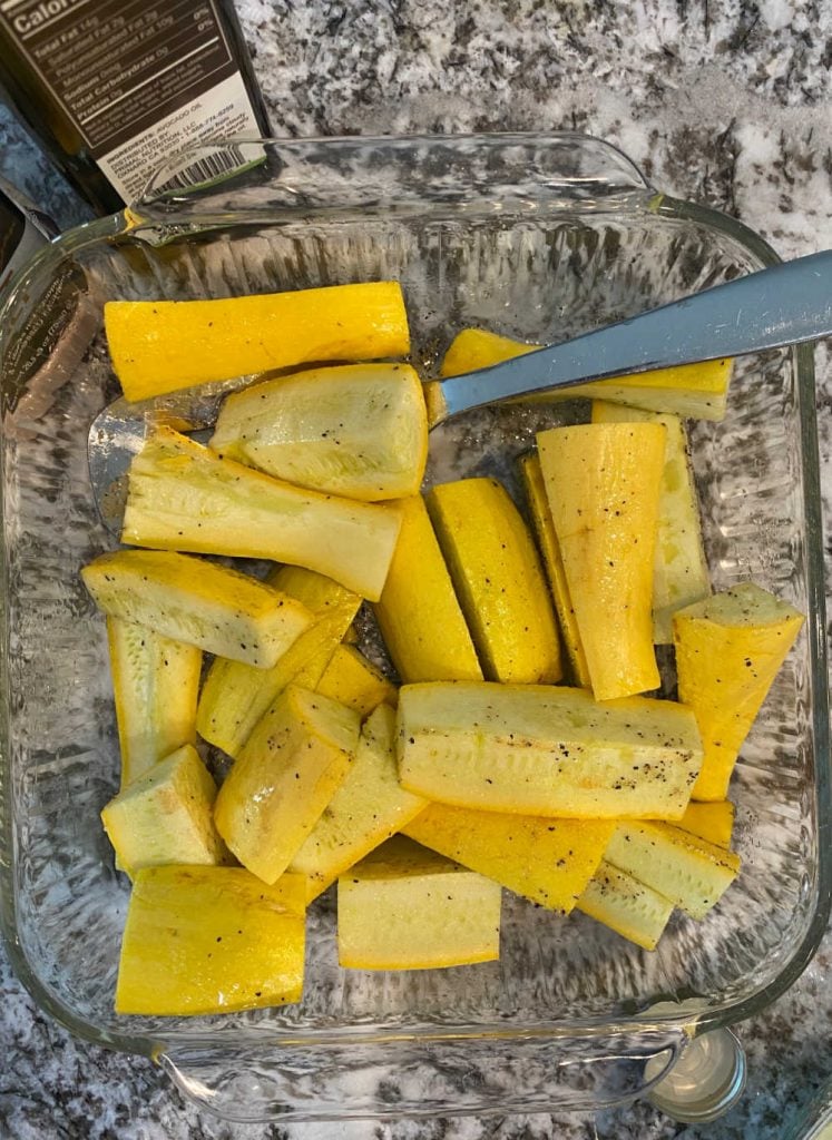 yellow squash in mixing bowl with avocado oil and seasonings