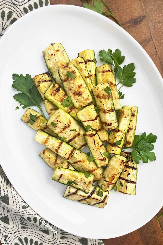 grilled zucchini spears with parsley on white platter