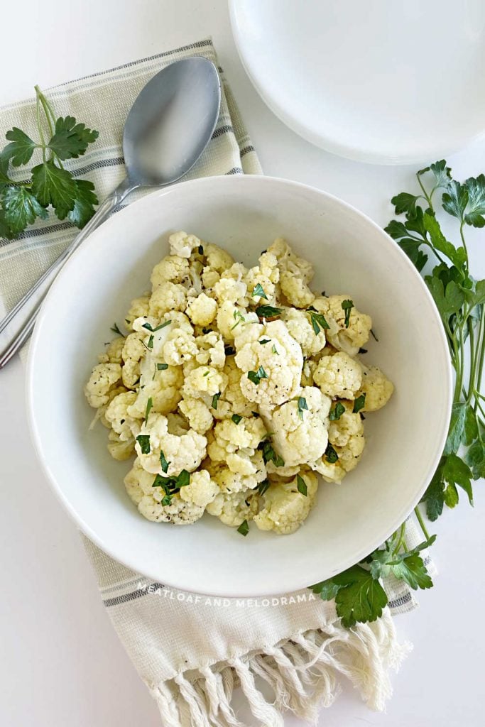 steamed cauliflower in white serving bowl with parsley