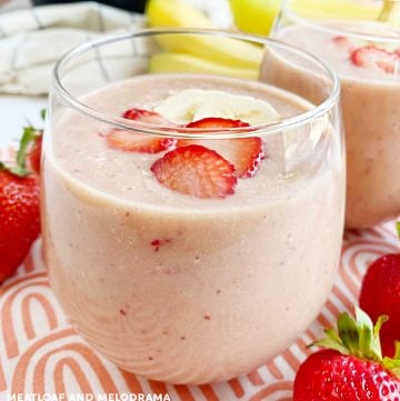 strawberry banana smoothie with peanut powder in a glass with fruit on the table