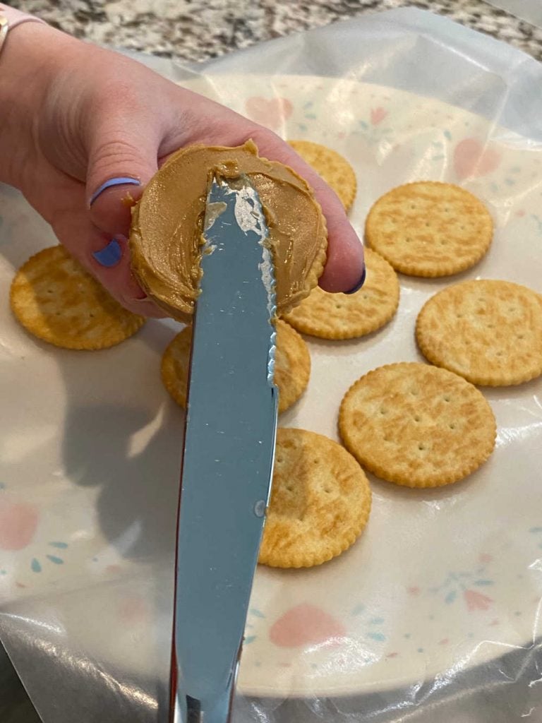 spread peanut butter on ritz cracker with knife