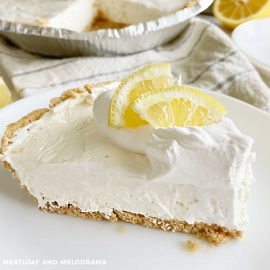 no bake lemonade kool aid pie with lemon slice and graham cracker crust on a white plate