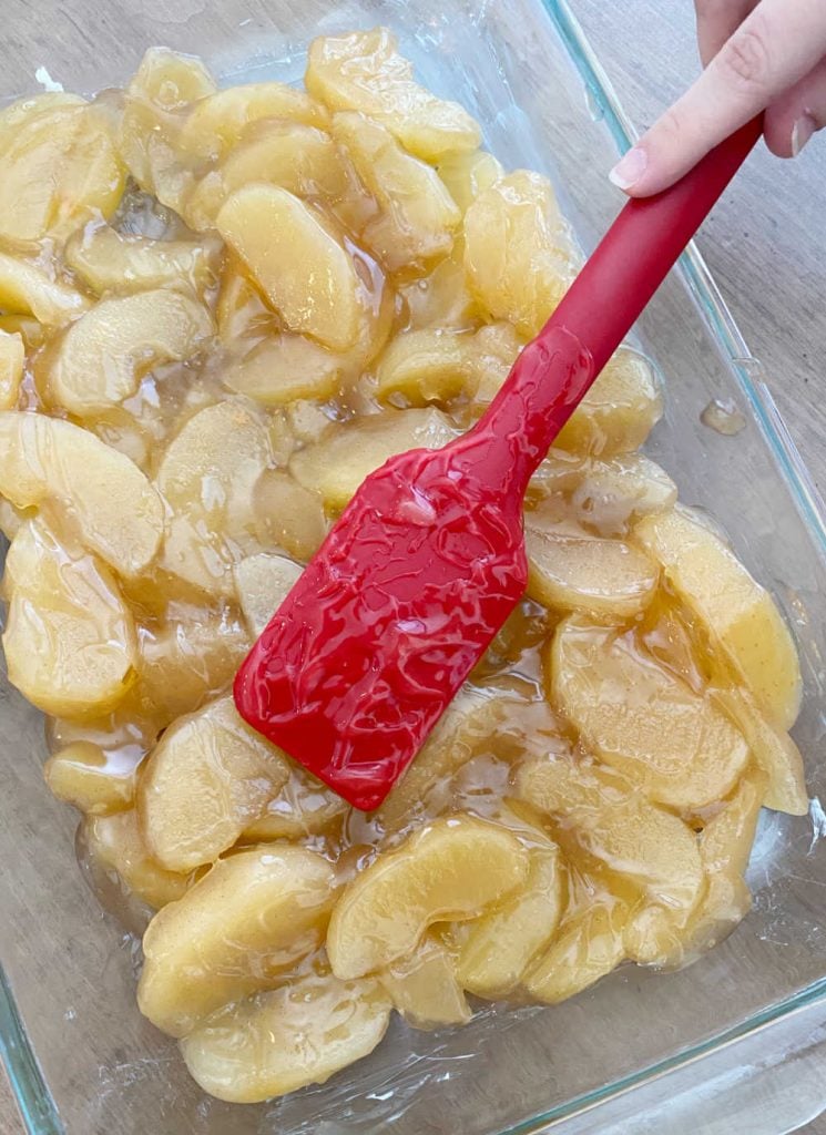 spread apple pie filling into baking dish with red spatula