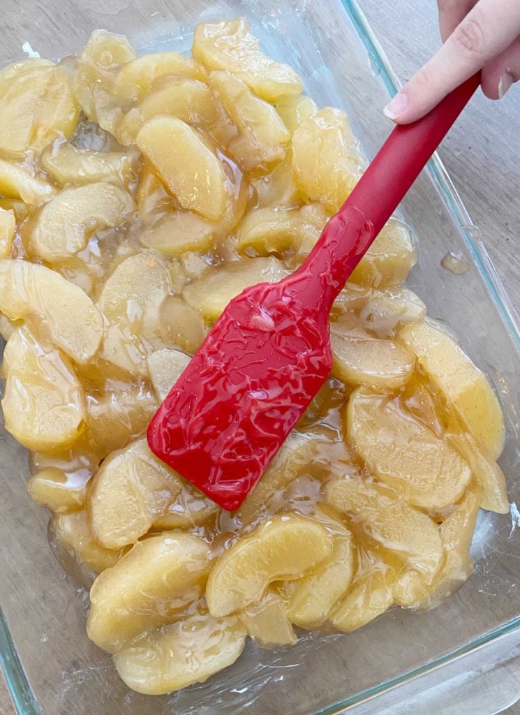 spread apple pie filling into baking dish with red spatula