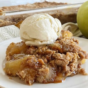 apple pie dump cake with scoop of vanilla ice cream and caramel sauce on a plate