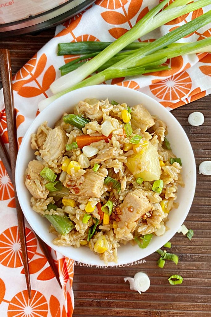 teriyaki chicken and rice in white bowl on the table with instant pot and chopsticks and green onions