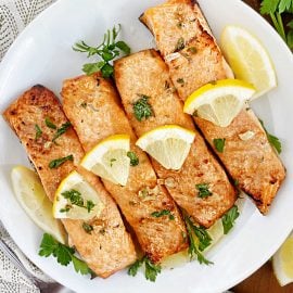 ninja foodie grill salmon on a plate with lemon garlic butter sauce and parsley
