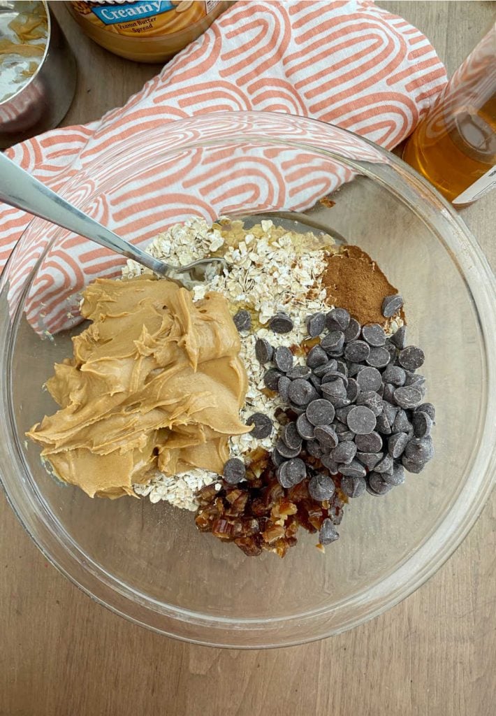rolled oats, peanut butter, honey, cinnamon, dates and chocolate chips in a mixing bowl