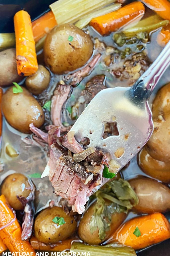 tender chuck roast on serving fork over crock pot
