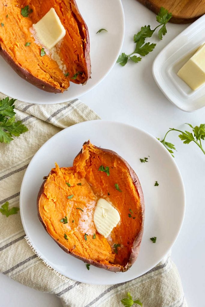 2 baked sweet potatoes with butter and parsley on table