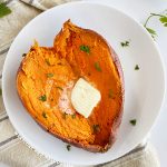 microwave sweet potato cut open on a plate with melted butter