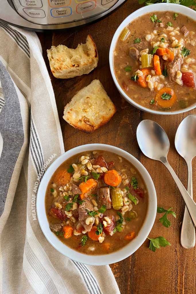 grandma's old fashioned beef barley soup in bowls on the table next to instant pot