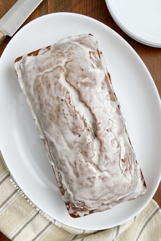 loaf of glazed pumpkin bread on white platter