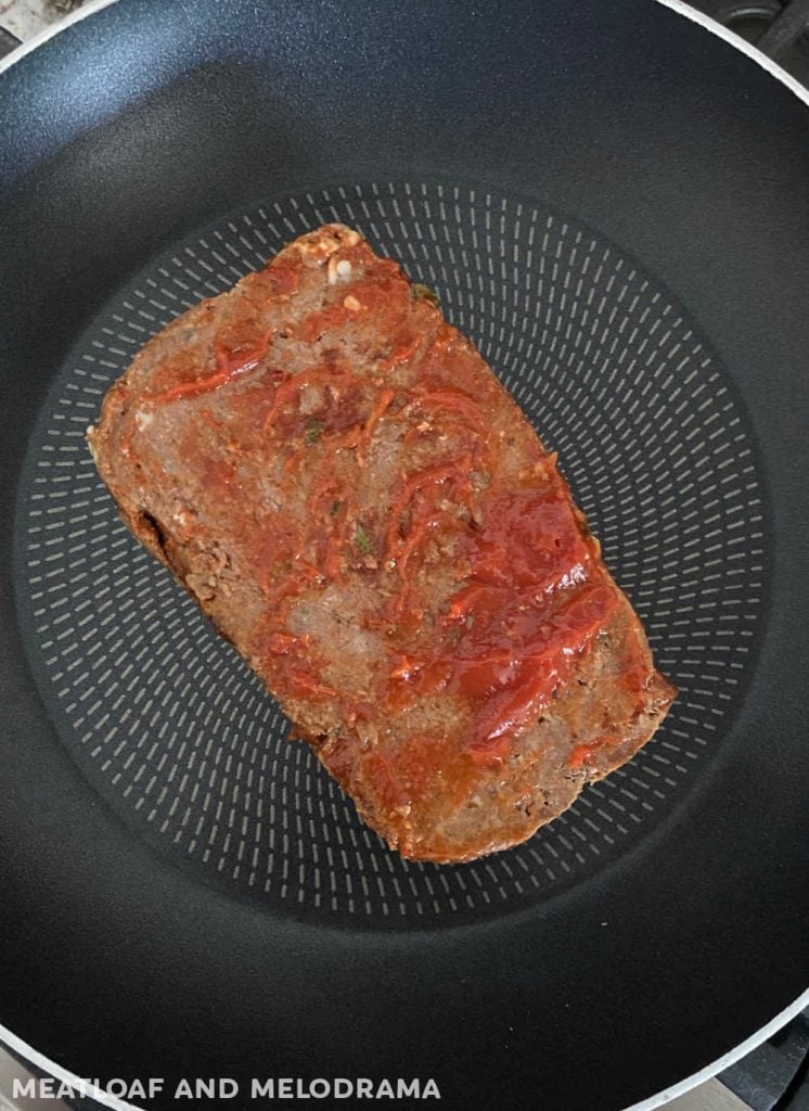 thick meatloaf slice with tomato sauce in frying pan