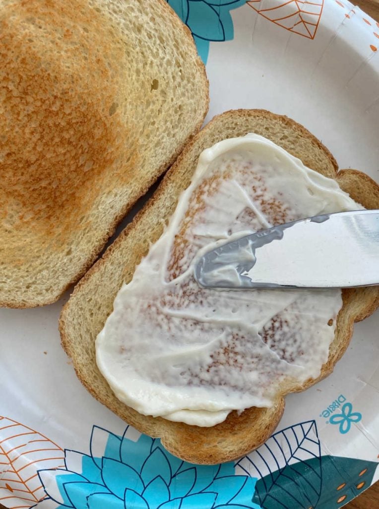 spread mayonnaise on toasted bread slice