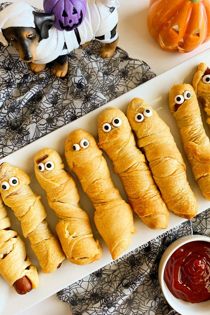 platter of halloween mummy dogs with candy eyes on the table
