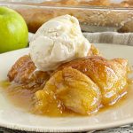 crescent roll apple dumplings with a scoop of vanilla ice cream and caramel sauce on a plate