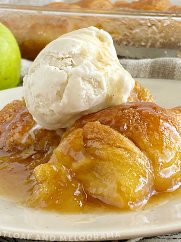 crescent roll apple dumplings with a scoop of vanilla ice cream and caramel sauce on a plate