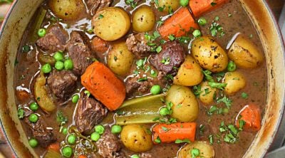 dutch oven beef stew with red wine, carrots and potatoes on the table