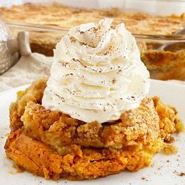 pumpkin dump cake with yellow cake mix topping and whipped cream on plate