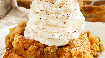 pumpkin dump cake with yellow cake mix topping and whipped cream on plate