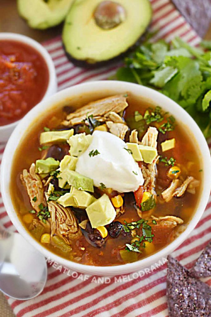 instant pot chicken taco soup with taco toppings and sour cream on the table in white bowl