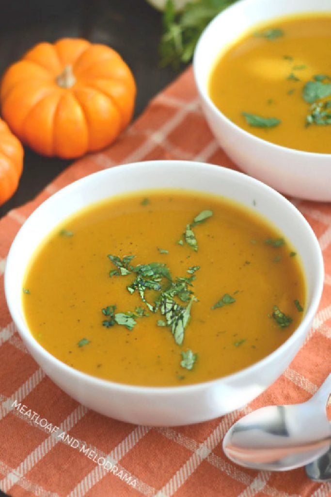 Instant pot pumpkin soup in white bowl with parsley on the table