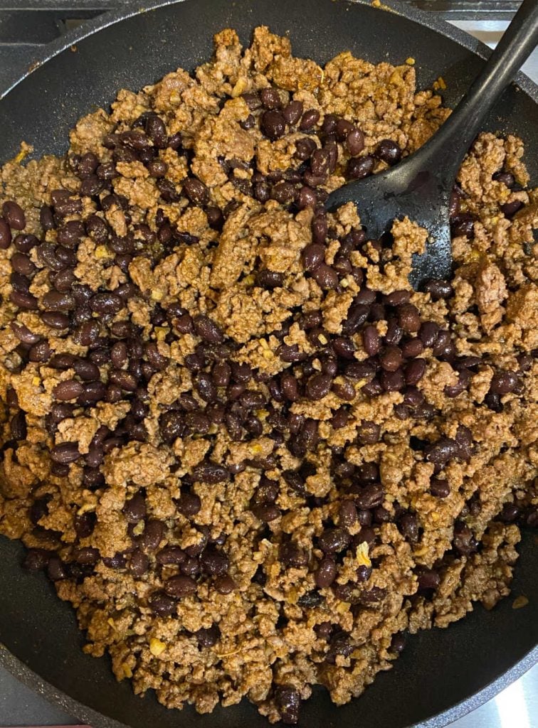brown ground beef and black beans in skillet
