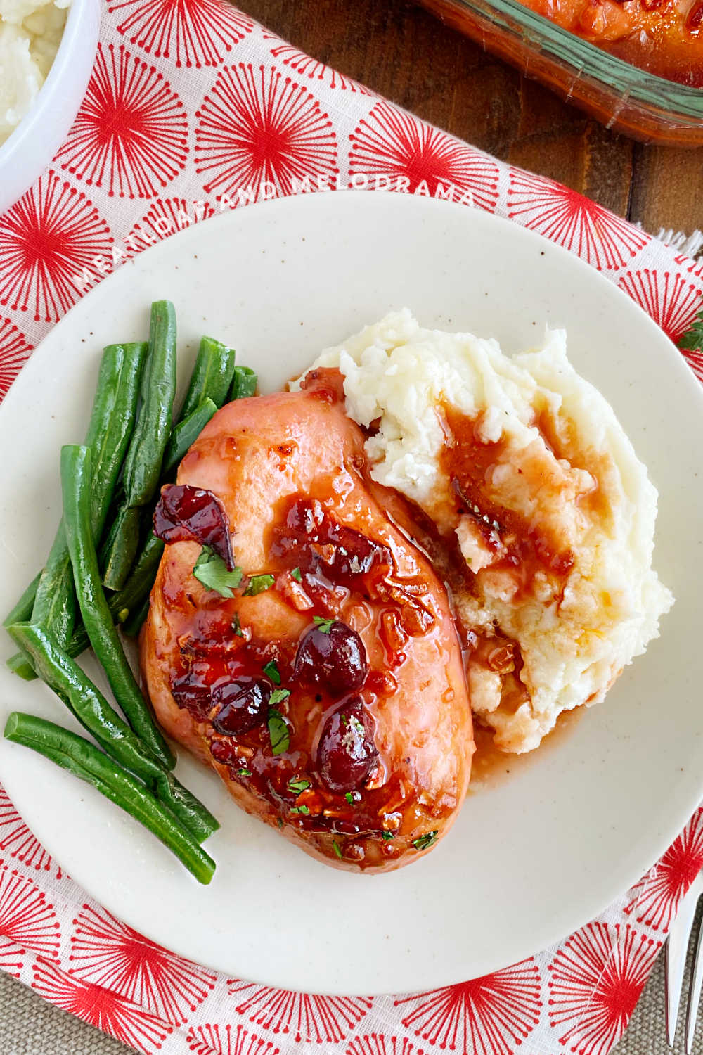 baked cranberry chicken breast with catalina dressing and whole berries on a plate with green beans and mashed potatoes