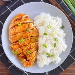baked teriyaki chicken breast with green onions and white rice on grey plate