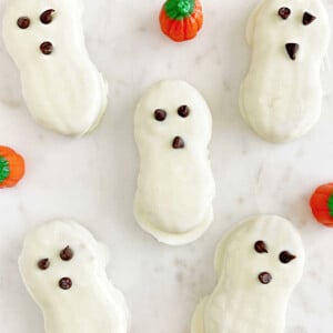 nutter butter ghost cookies for halloween with candy pumpkins on marble surface