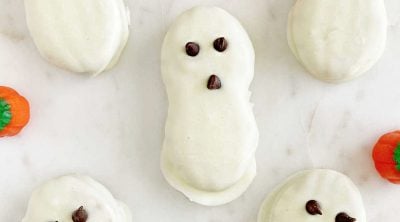 nutter butter ghost cookies for halloween with candy pumpkins on marble surface