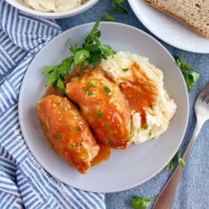 2 cabbage rolls (slovak halupki) in tomato soup sauce with mashed potatoes on plate