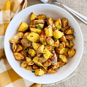 crispy air fryer baby potatoes with parmesan cheese and parsley in white serving bowl