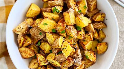 crispy air fryer baby potatoes with parmesan cheese and parsley in white serving bowl