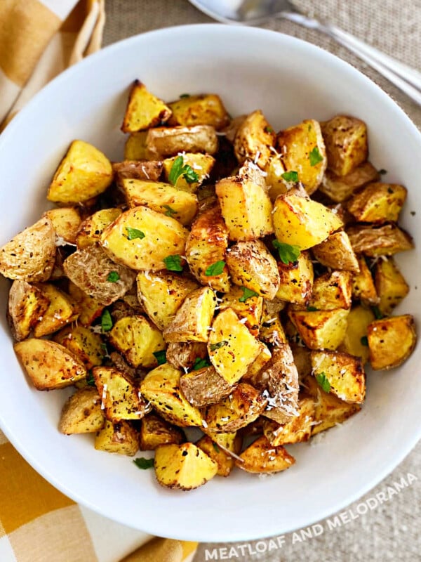 crispy air fryer baby potatoes with parmesan cheese and parsley in white serving bowl
