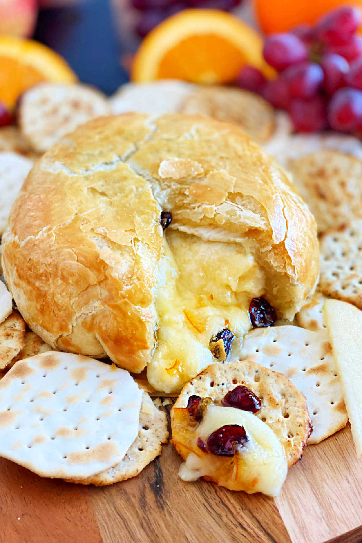 baked brie in puff pastry cut open with melted cheese and cranberries on crackers