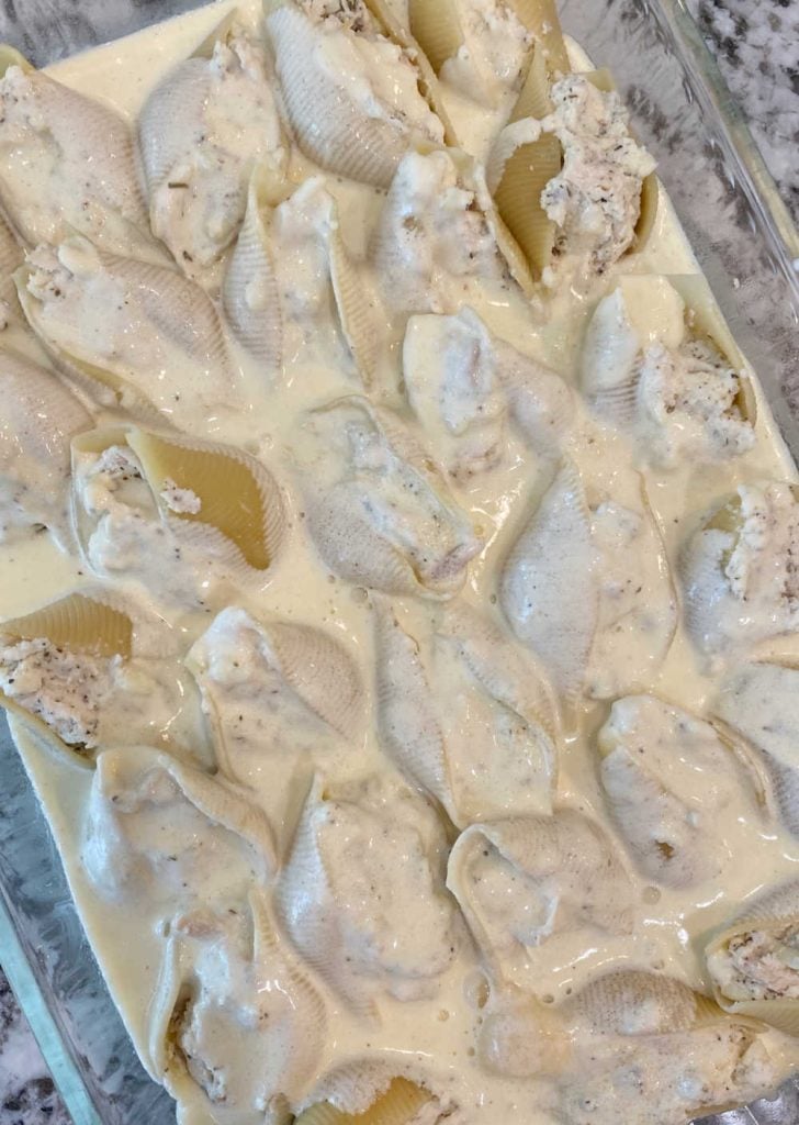 chicken ricotta stuffed shells with homemade Alfredo sauce in baking dish