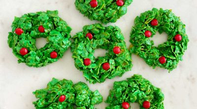 Christmas cornflake wreath cookies with red candies on cake stand