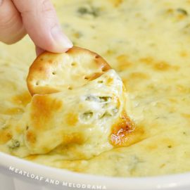 round cracker dipped into hot cheesy spinach dip