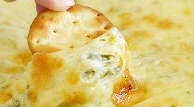 round cracker dipped into hot cheesy spinach dip