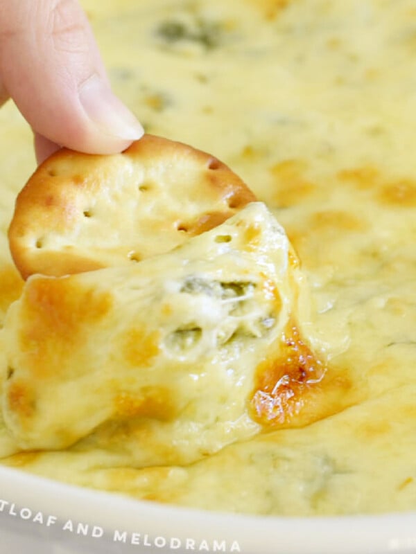 round cracker dipped into hot cheesy spinach dip